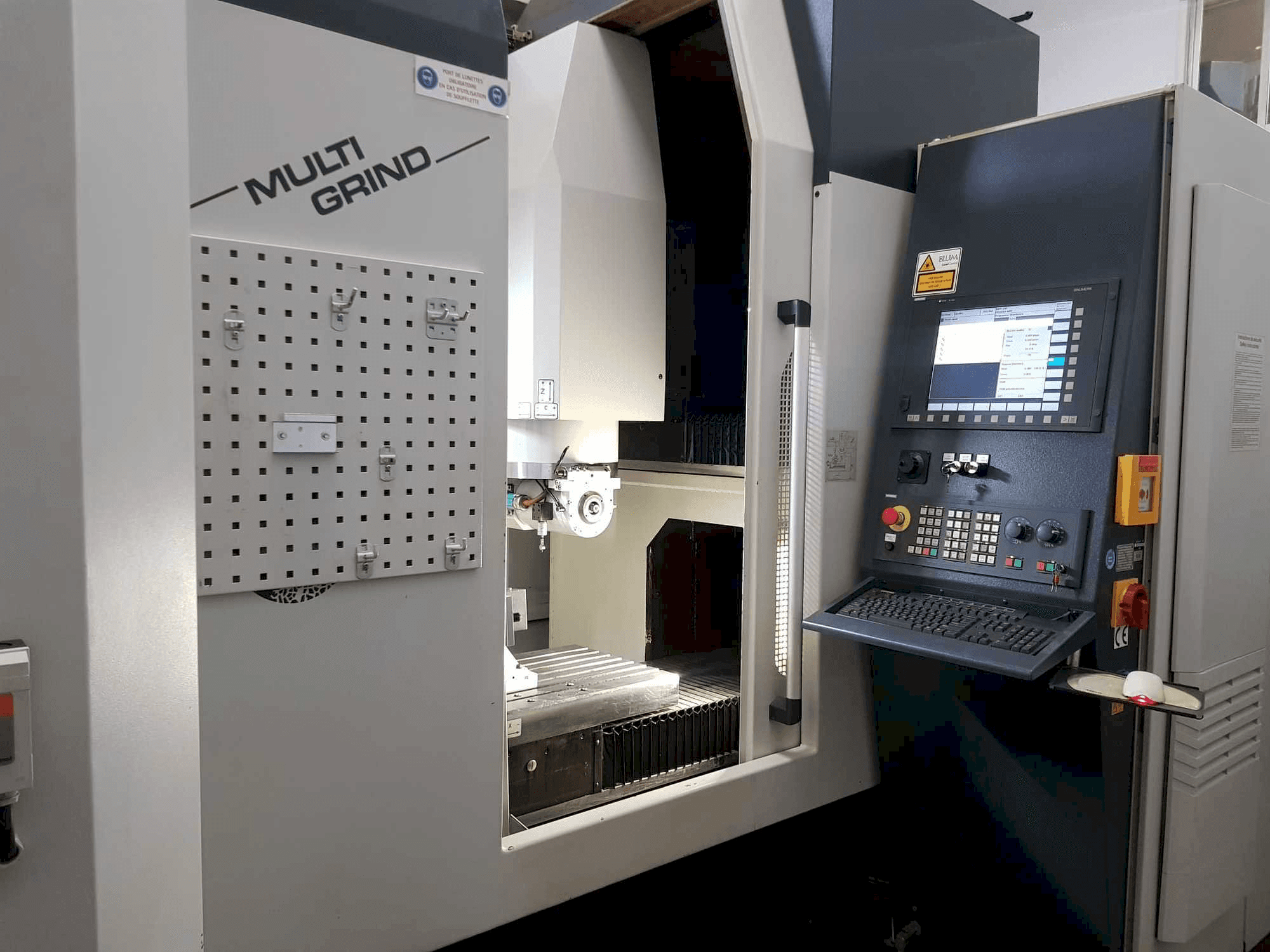 Multi Grind CNC-kone etukuvassa, jossa on ohjauspaneeli, säilytyspaneeli ja avoin työskentelyalue.